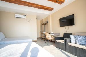 a hotel room with a bed and a couch and a tv at Sofia - Summer Coastal Suites in Bacnotan