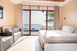two beds in a room with a view of the ocean at Sofia - Summer Coastal Suites in Bacnotan +78 photos