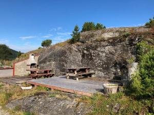 two picnic tables sitting next to a rock wall at Skjevlingsnes sjøhus in Tingvoll +8 photos