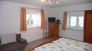 ein Schlafzimmer mit einem Bett und einem Sofa sowie zwei Fenstern in der Unterkunft Ferienhof Schugg in Missen-Wilhams