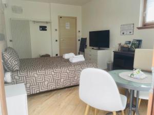 a room with a bed and a table and a television at Il Vigneto Rooms & Breakfast - Valtellina Panoramic View in Castione Andevenno