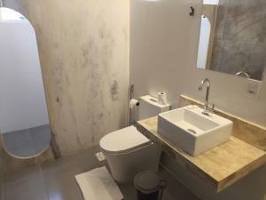 a bathroom with a sink and a toilet and a mirror at Gyn Suítes - Suítes novas e funcionais in Goiânia