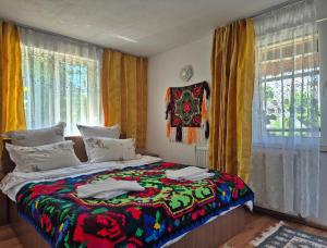 a bedroom with a bed with a colorful blanket on it at Casa Grigor in Călineşti