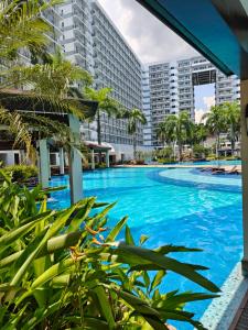 a large swimming pool with palm trees and buildings at MOA shell residences - JOSH in Manila