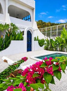 a house with a swimming pool and pink flowers at Bnaya Villas Riverside in Amed