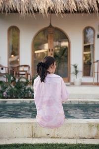 a woman sitting on a curb in front of a house at Bellis Garden in Kuta Lombok +33 photos