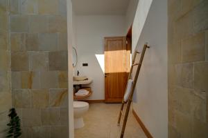a bathroom with a toilet and a stone wall at Bellis Garden in Kuta Lombok