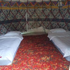 a room with two beds and a wall at Kapchygai Yurt Camp in Dzhetyoguz +13 photos