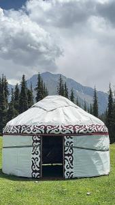 a large tent in a field with mountains in the background at Kapchygai Yurt Camp in Dzhetyoguz