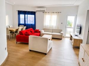 a living room with a red couch and white chairs at TchaoPremium in Lomé
