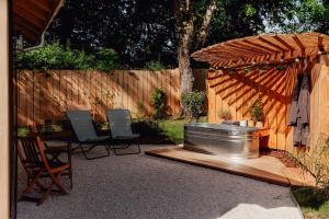 a backyard with a hot tub and chairs and a fence at Le Clos des Pies in Le Pin