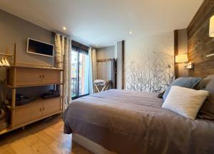 a bedroom with a bed and a tv on the wall at Homency - Résidence Ménandière V2 spot in L'Alpe-d'Huez