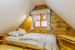 a bed in a wooden room with a window at Chalupa Vysoký Potok in Malá Morava