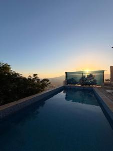 a swimming pool with a sunset in the background at Luxury Mountain Chalet with Private Pool Lionden Jerash in Jerash
