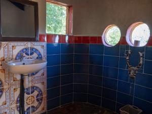 a blue tiled bathroom with a sink and two windows at Tsarasoa Lodge in Ambalavao +26 photos