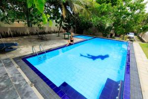 a woman is swimming in a large swimming pool at Soulinn Regina Weligama in Weligama