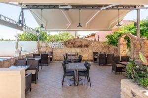 a restaurant with tables and chairs and a stone wall at Evina Rooms & Suites in Kokkini Khanion