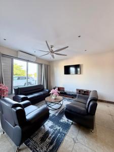 a living room with black leather furniture and a flat screen tv at Bountiful Estates Fantasy in Nadi