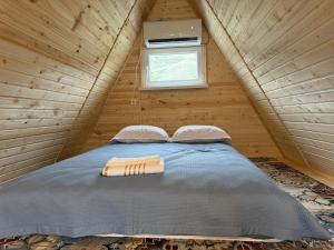 a bed in a wooden cabin with a window at UYA A-farme in Saty