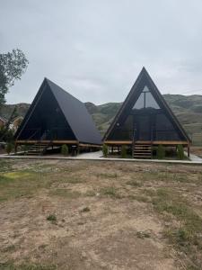 a large building with a black roof with hills in the background at UYA A-farme in Saty