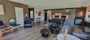 a living room with a couch and chairs and a kitchen at Kastanjegaarden in Ansager
