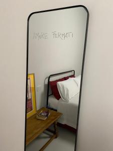 a mirror in a bedroom with a bed and a table at Casa Margo in Campobasso