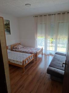 two beds in a room with wooden floors and windows at Apartman Leka in Donji Bogdašići