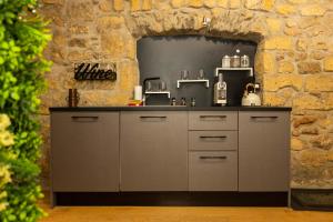 a kitchen with grey cabinets and a stone wall at Il Butto - Loft Etrusco in Tarquinia