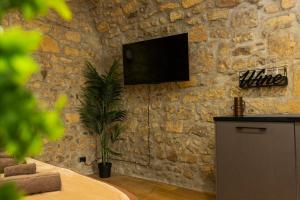 a living room with a tv on a stone wall at Il Butto - Loft Etrusco in Tarquinia