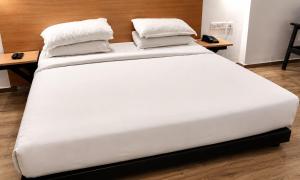 a white bed with two pillows on top of it at Hotel Somani Wakad in Méribel Village