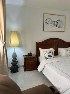 a bedroom with a bed and a table with a lamp at Le bungalow by mk in Nzogobeyork