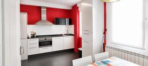a kitchen with white cabinets and red walls at Apartamento La Cava in Calahorra