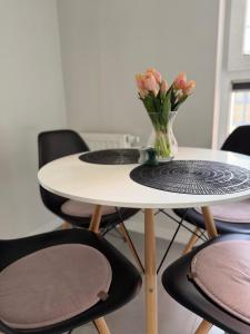 a table and chairs with a vase of flowers on it at APARTAMENT TETRIS - CENTRUM - Garaż in Kielce