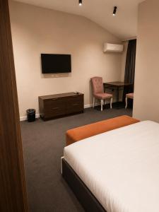 a hotel room with a bed and a flat screen tv at Central City Department Hotel in Baku