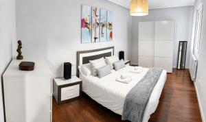 a white bedroom with a bed and a night stand at Apartamento La Cava in Calahorra +16 photos