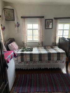 a bedroom with a bed and two windows at Старий Хутір - Етно Хатина 1914 in Oposhnya +2 photos