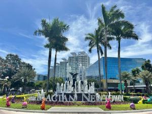 a fountain in a park with palm trees and a building at Mactan Newtown Condo Rental in Punta Engaño