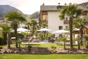 a resort with palm trees and tables and umbrellas at Hotel Schallerhof in Tesimo