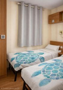 a room with two beds and a curtain at camping des 7 fonts in Agde +9 photos