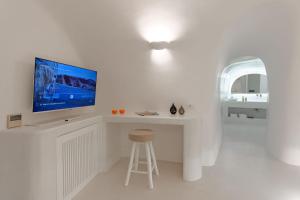 a white living room with a tv on a white desk at EG Cave Houses in Éxo Goniá