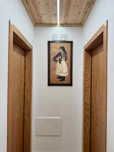 a painting of a woman on a wall next to two doors at Old Mill Heritage Hotel in Ndërlysaj