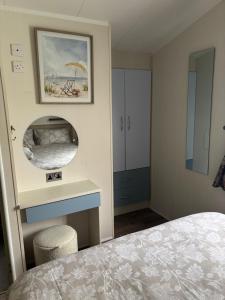 a bedroom with a bed and a mirror at Luxury 2 Bed Caravan With Decking - Sleeps 4 - at Broadland Sands Park in Lowestoft
