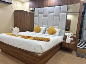 a bedroom with a large bed with a large headboard at Surmila International Hotel in Āsansol +5 photos