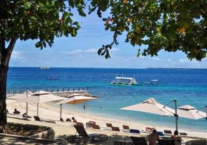 a beach with umbrellas and a boat in the water at Mactan Newtown Condo Rentals in Punta Engaño