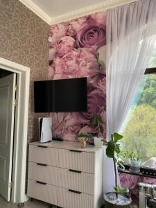 a tv on a dresser in a room with flowers at Aura in Dzerzhinskoye
