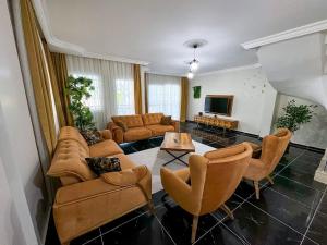 a living room with a couch and chairs and a tv at Villa Incir in Kuşadası