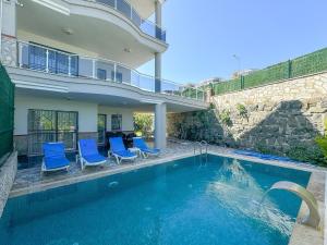 a swimming pool with blue chairs and a house at Villa Incir in Kuşadası +22 photos