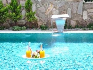 a pool with two glasses of orange juice and a fountain at Villa Incir in Kuşadası