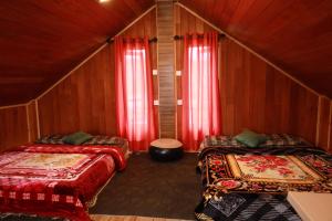 two beds in a room with red curtains at The Cloud-Line Cabana in Nuwara Eliya