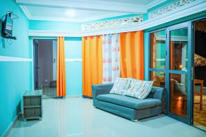 a living room with a blue couch and orange curtains at Marionel Hôtel in Ampilahoa